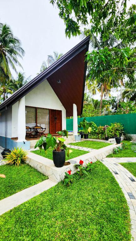 a house with a black roof and a garden at Pearl Villa Katunayake in Katunayaka