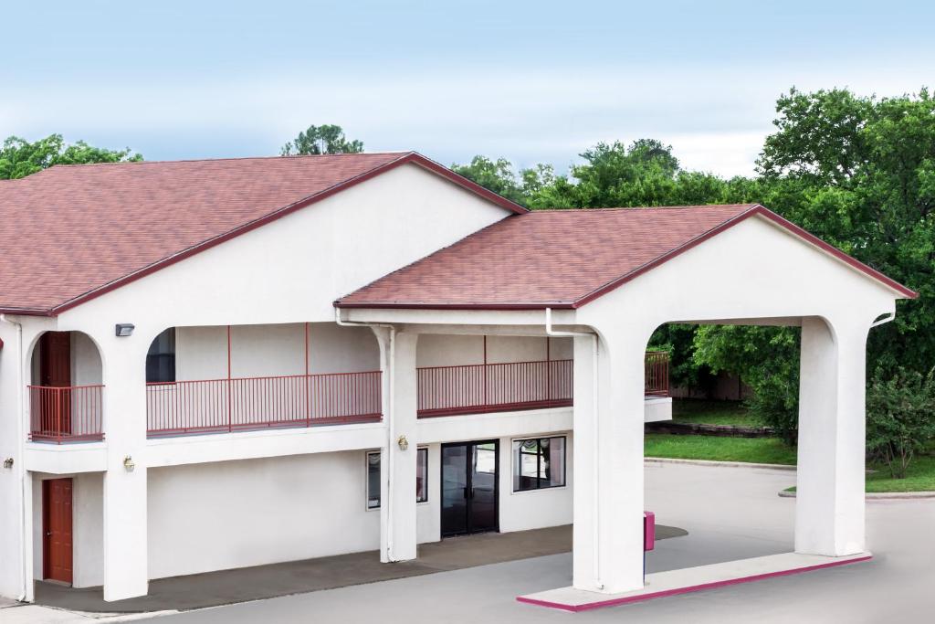 a white building with a red roof at Deluxe Inn Denton in Denton