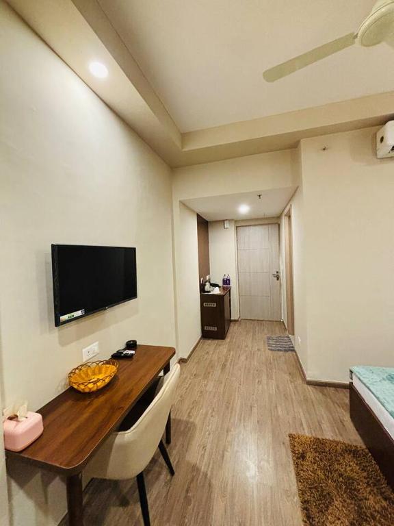 a room with a table and a television on the wall at The Pineapple Suite with Gorgeous Views in Greater Noida