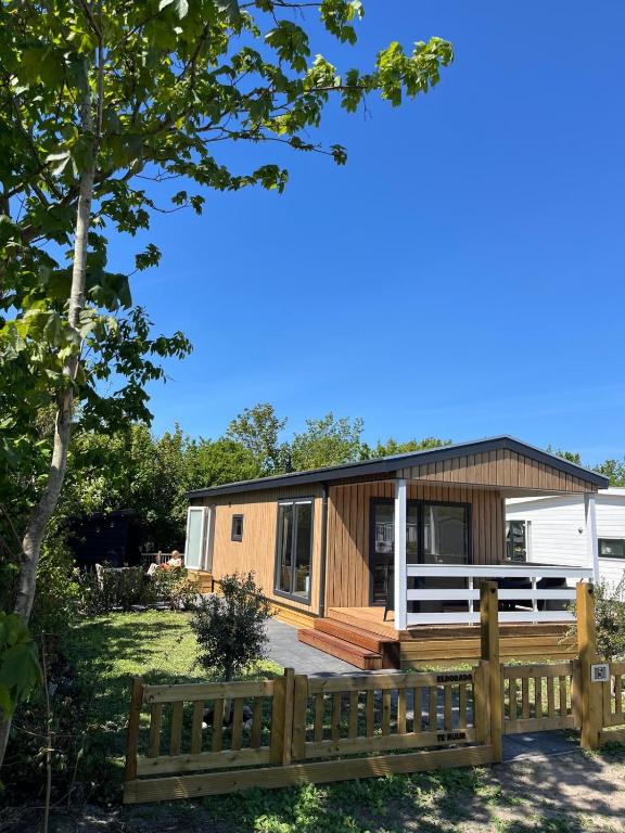 a tiny home with a wooden fence and a house at Eldorado in Petten