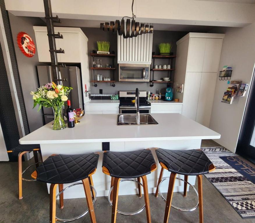 a kitchen with a white island with bar stools at Exclusive Modern Suite view in Kamloops