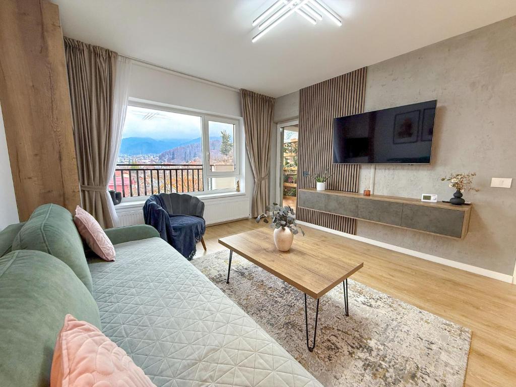 a living room with a green couch and a large window at Mountain and City View with Underground Parking in Braşov