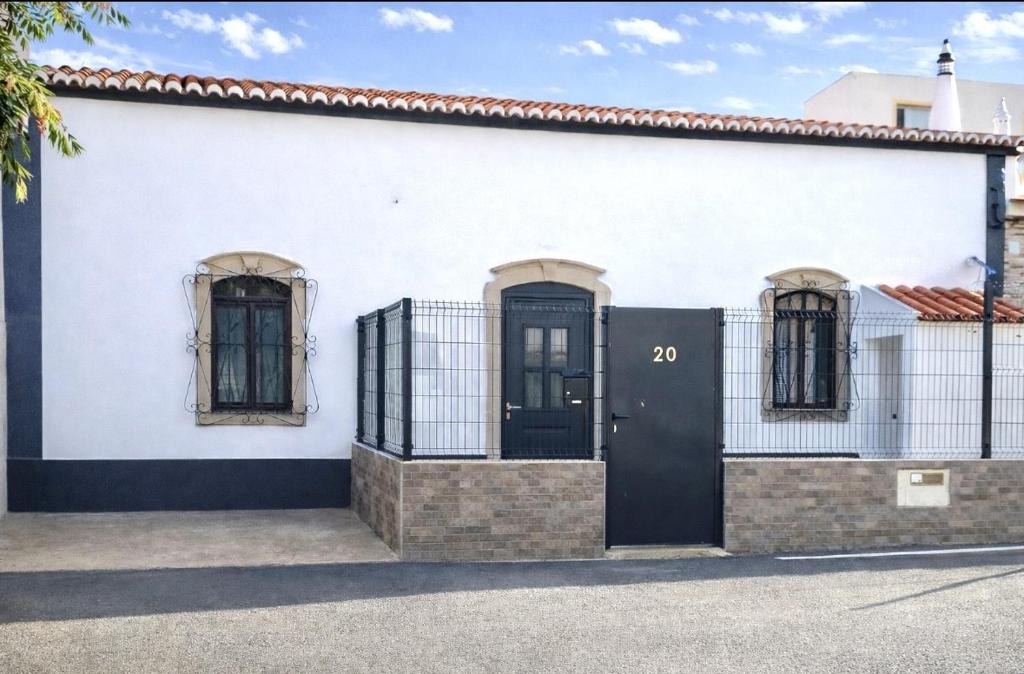 a white building with a black door and two windows at Casa luz e conforto-Casa 20 in Almancil