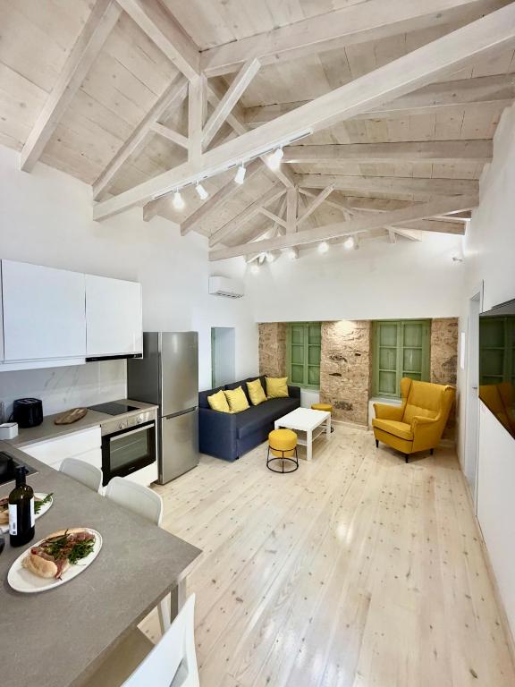 a kitchen and living room with a table and yellow chairs at Central Suites Aegina 5 in Egina