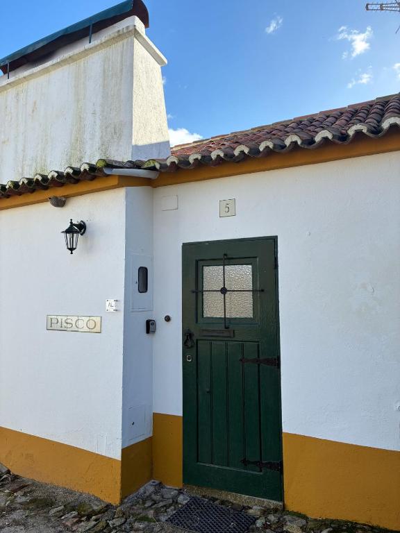 a green door on the side of a white building at Pisco Charming House - Alter Pedroso in Alter do Chão