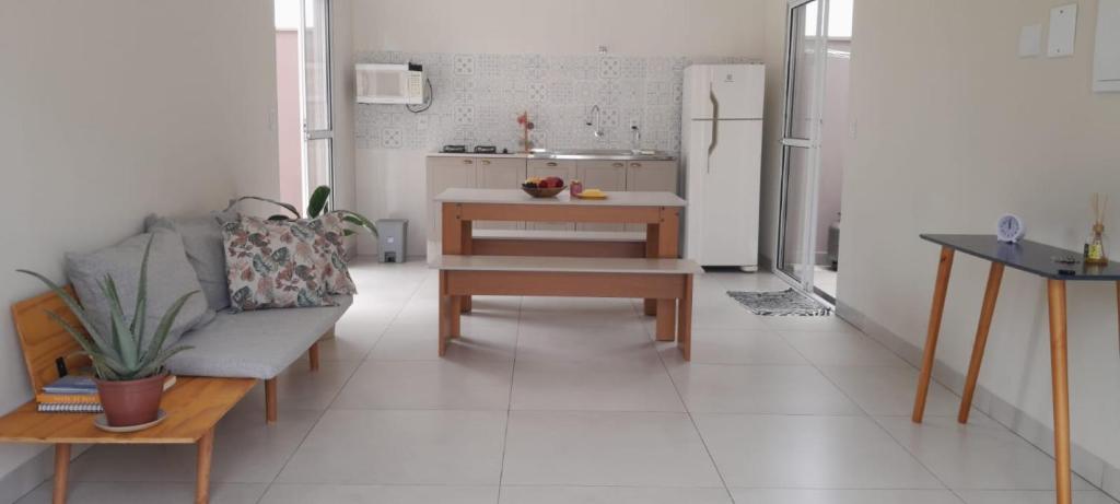 a kitchen with a couch and a table and a refrigerator at Garden House Canastra in Delfinópolis