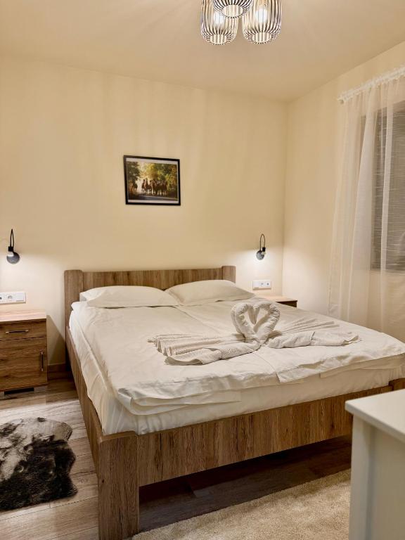 a bedroom with a large bed with white sheets and a chandelier at AKZ Apartman in Makó