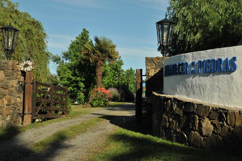 a sign on a stone wall next to a road at Amanecer en las Piedras in Tandil