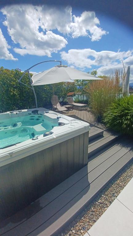 a large hot tub on a deck with an umbrella at Comfort Rooms mit Whirlpoolzugang in Romanshorn