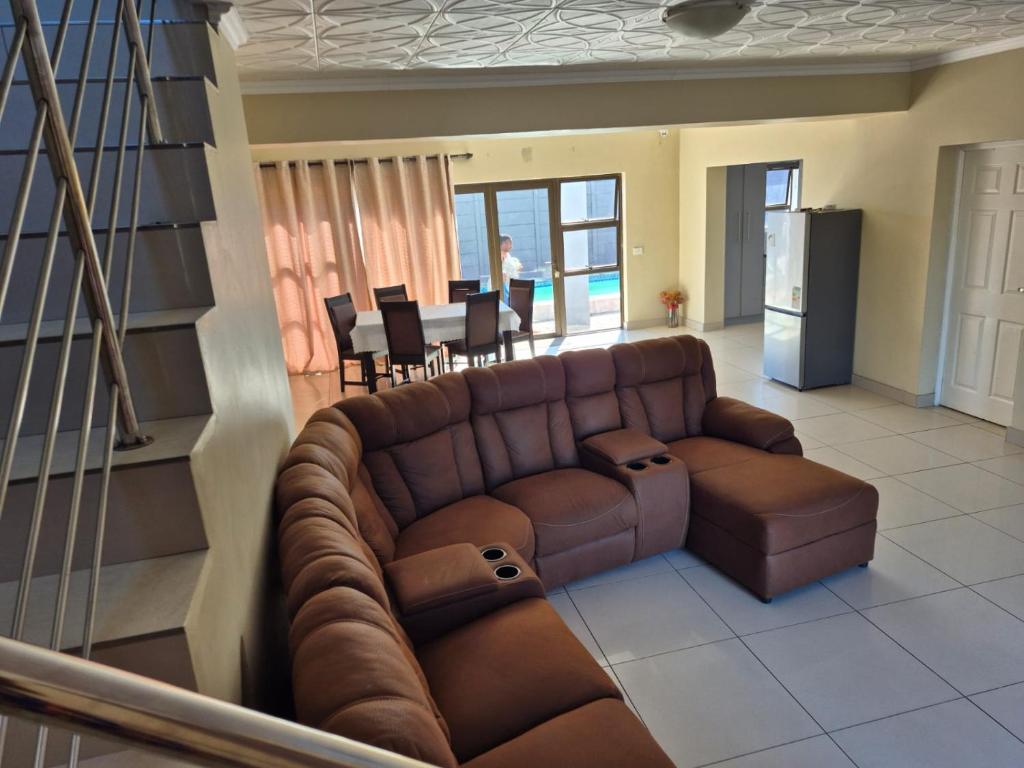 a living room with a brown couch and a kitchen at Pemba's residence in Cape Town