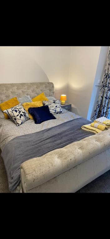 a large bed with yellow pillows on top of it at Cambridge Villa St Annes in Lytham St Annes