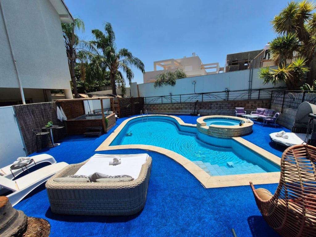 a large swimming pool with chairs and a swimming pool at Private jacuzzi suite rosh pina in Rosh Pinna