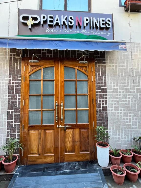 a pair of wooden doors on a building with potted plants at Peaks n Pines in Nainital