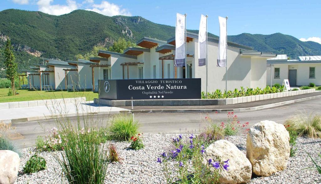 a sign in front of a building with mountains in the background at Costa Verde Natura in Clusane sul Lago