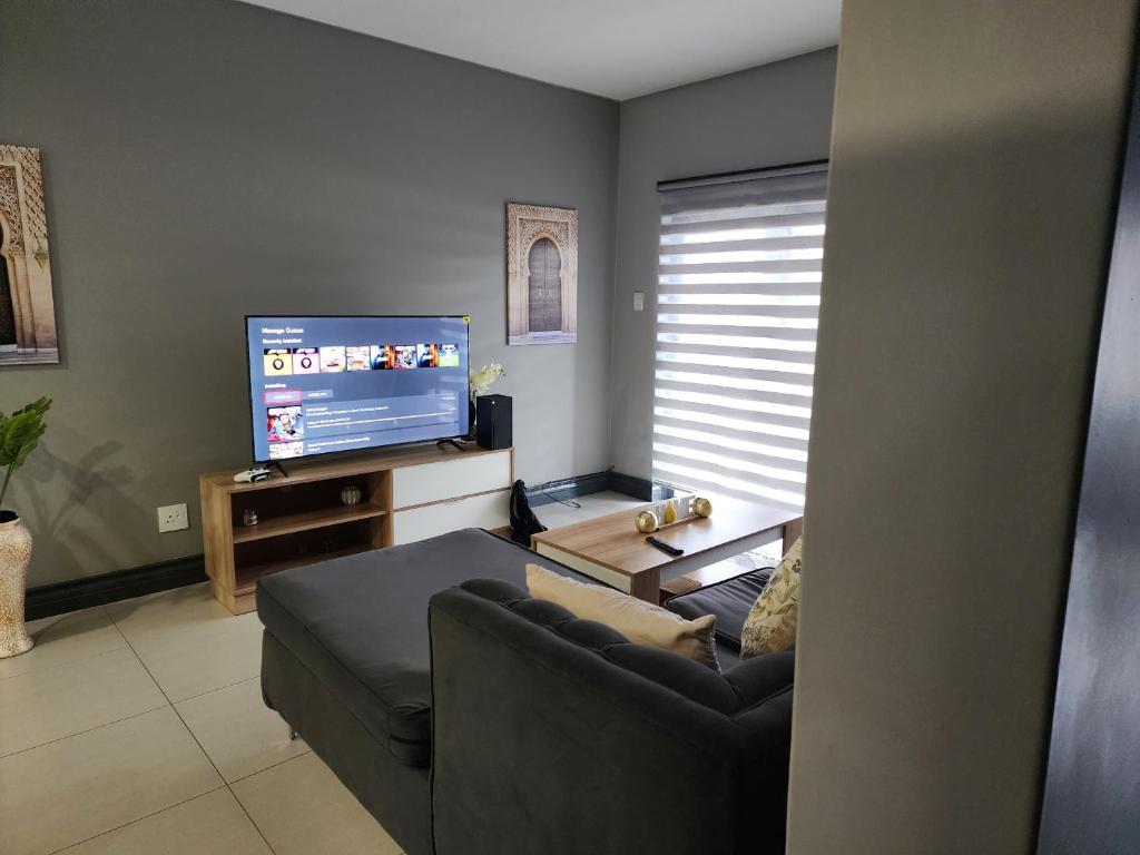 a living room with a couch and a flat screen tv at Leaf Mbabane CBD Apartment in Mbabane
