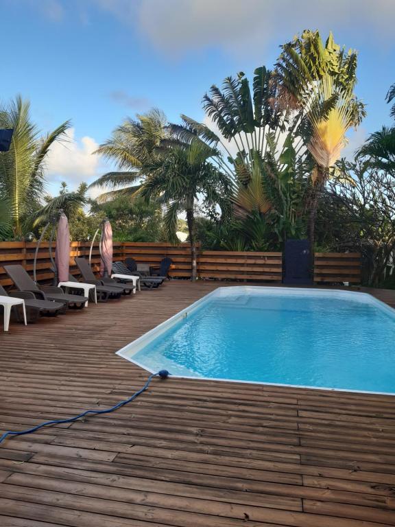 a swimming pool on a deck with chairs and palm trees at Gîte HIBISCUS in Saint-François