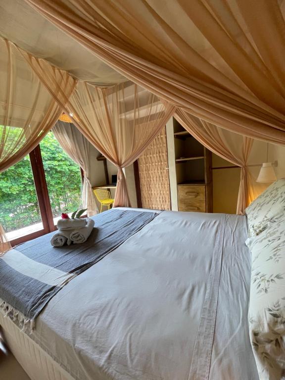 a bed in a room with a window at MAHAGUA Casa Holística - Jambreiro, Caraiva, BA in Porto Seguro