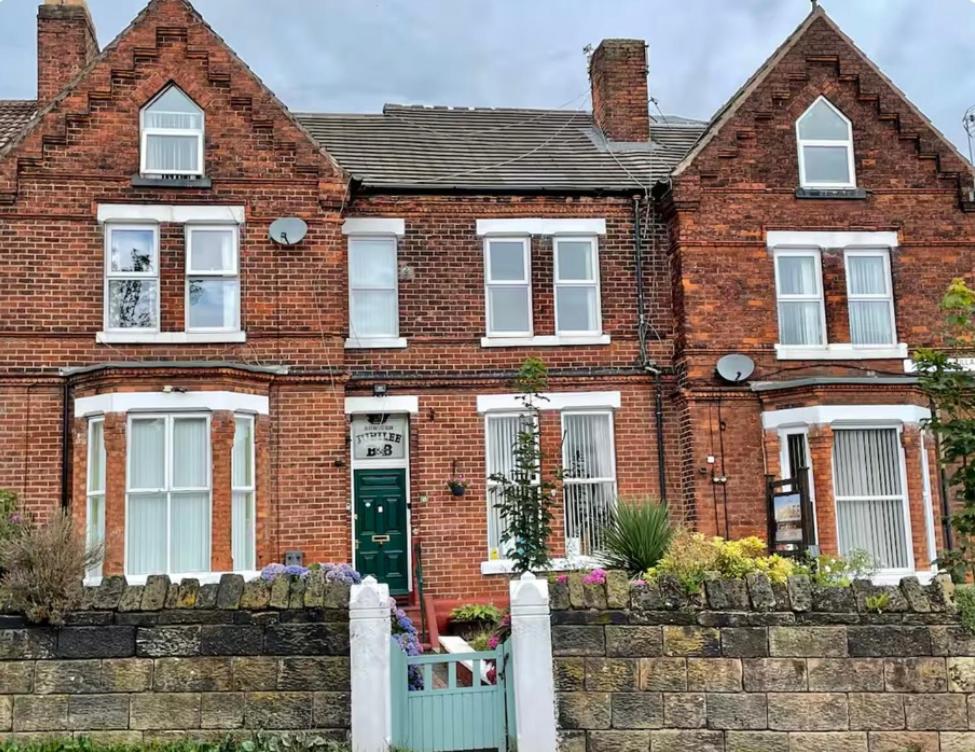a brick house with a white fence in front of it at Runcorn Jubilee Guest House in Runcorn