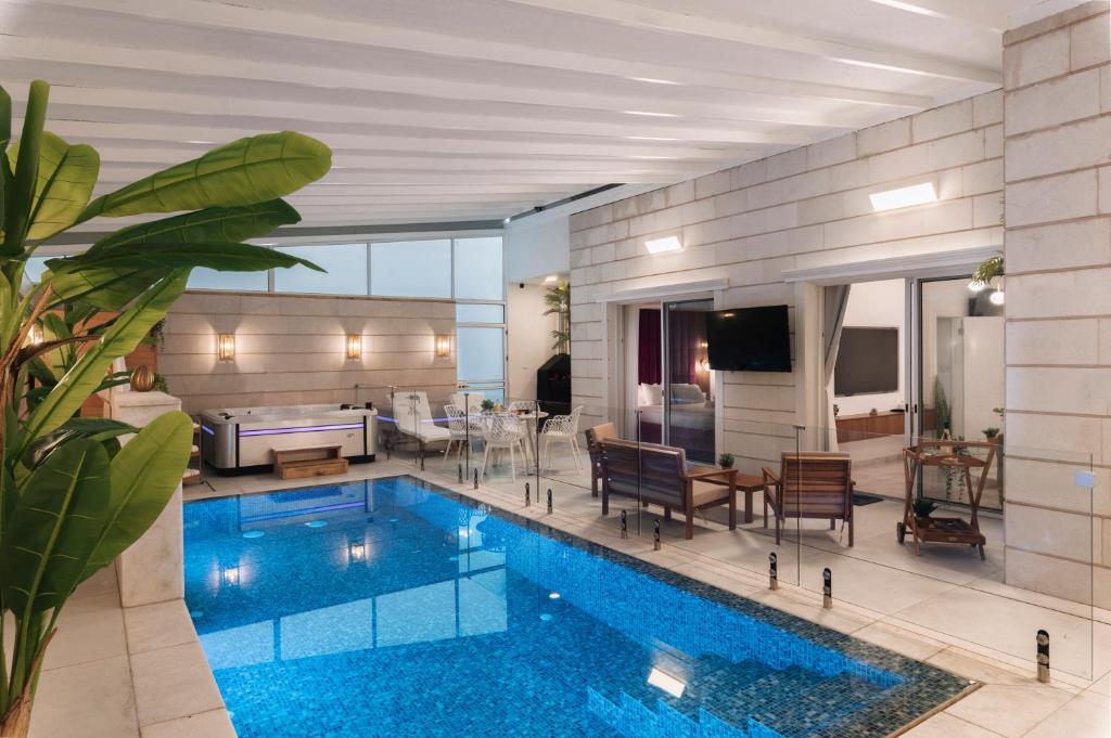 a living room with a swimming pool in the middle of a house at מילה בוטיק - סוויטה מהממת עם 2 חדרי שינה, מתחם מקורה עם בריכה מחוממת, ג'קוזי ספא וסאונה! in ‘Ein Ya‘aqov
