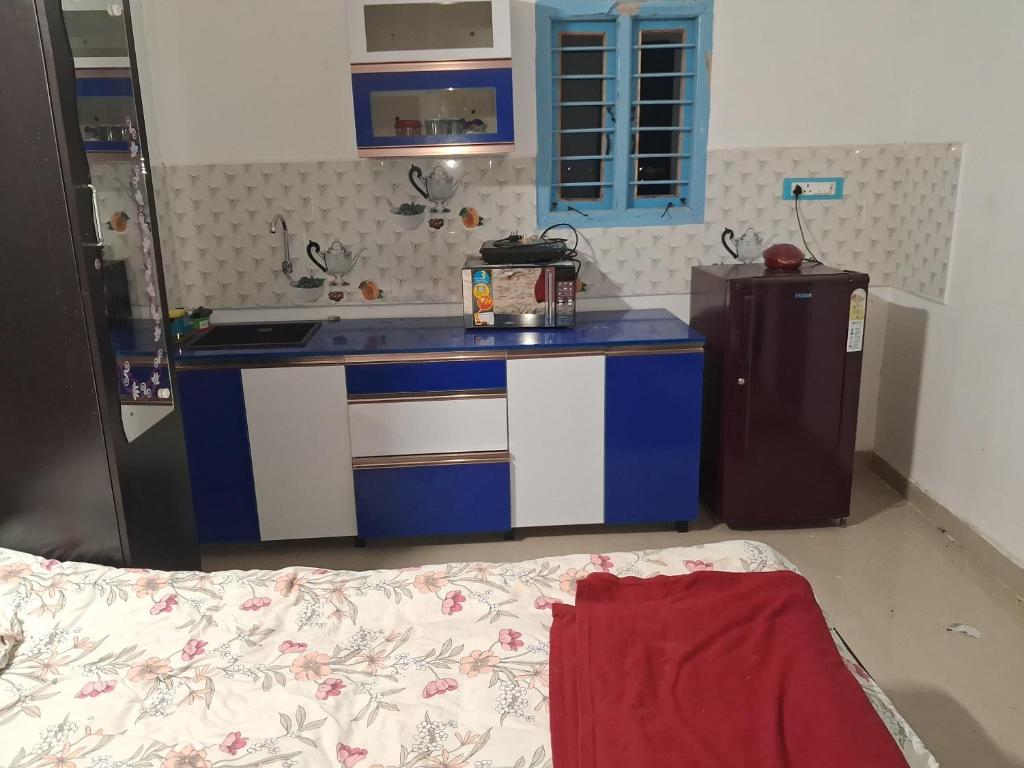 a kitchen with blue and white cabinets and a refrigerator at ViRa Farm in Sūlagiri