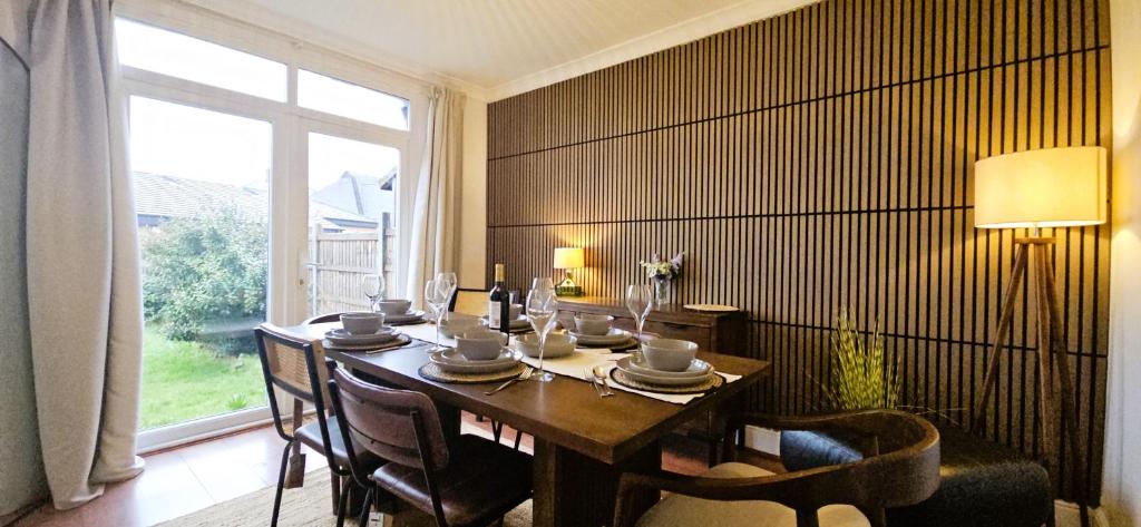 a dining room with a table and a large window at Spacious Home Near Wembley, Free Parking, Close to Tube, Garden in Pinner