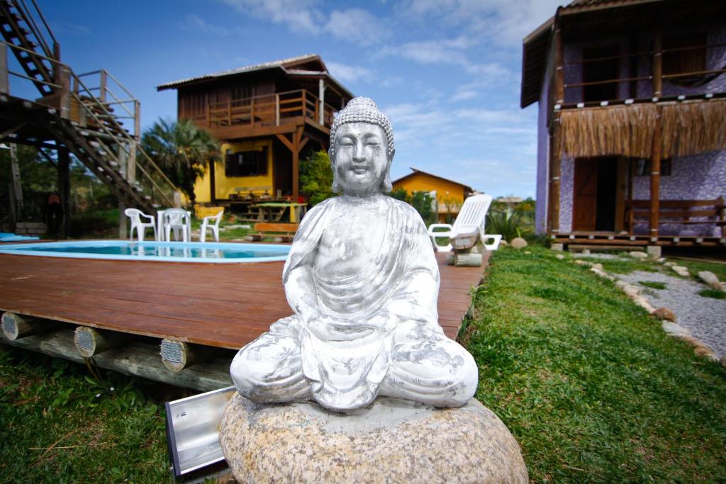 a statue of a man sitting on a rock in front of a house at Sunset Lagoon Praia do Rosa in Praia do Rosa