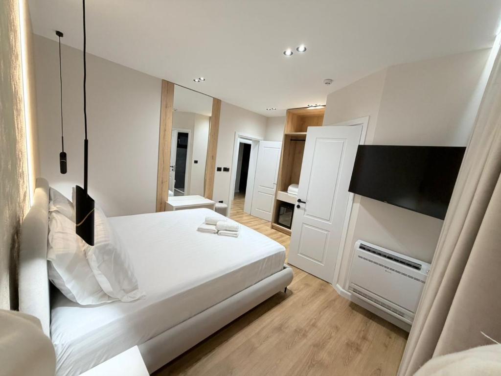 a bedroom with a white bed and a flat screen tv at Velour Boutique Hotel Durres in Durrës