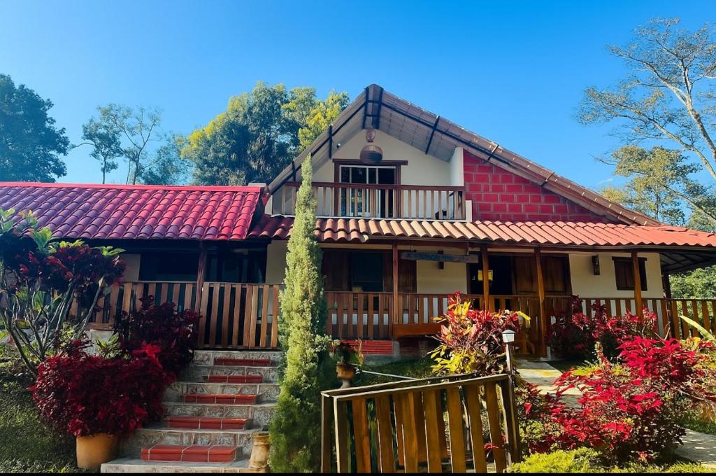 a house with a red roof and some flowers at Cabane Finca la Gloria in San Vicente de Chucurí