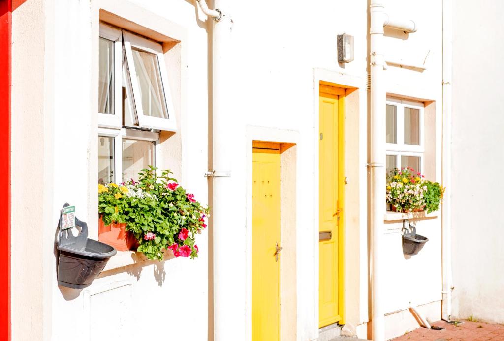 a white building with flower boxes and a yellow door at Ocean View - 2 Bedroom Townhouse in Bundoran
