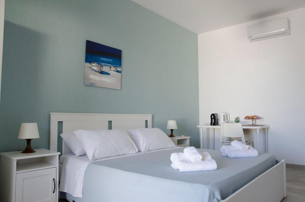 a bedroom with a white bed with towels on it at Residence La Perla - Marzamemi & Sea - Homie Livings in Marzamemi