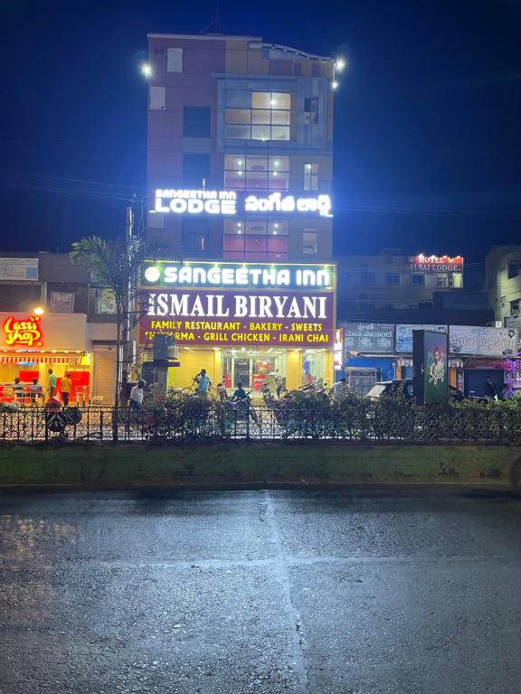 a large building with a sign on it at night at SangeethaInn in Ongole