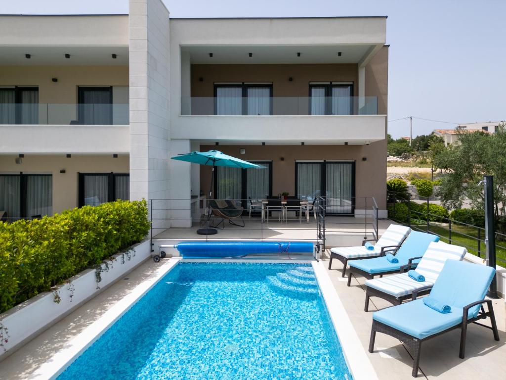 a villa with a swimming pool in front of a building at Villa Olive Tree in Vinišće