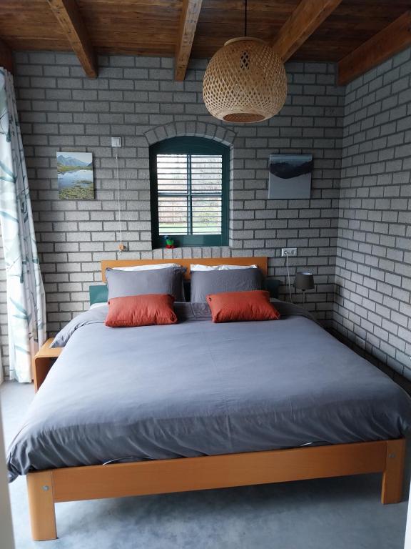 a bedroom with a large bed in a brick wall at Gastenverblijf De Lopende Eend in Boxtel