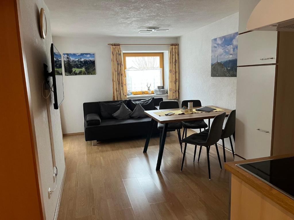 a living room with a black couch and a table at Haus Alpenblick in Bichlbach