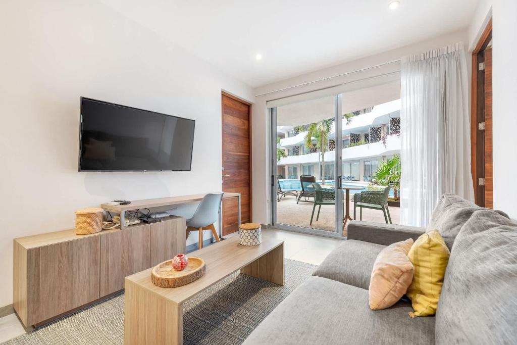 a living room with a couch and a tv at Swim-up 1-bedroom apartment in Playa del Carmen