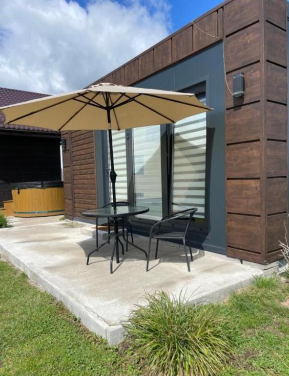 a patio with a table and an umbrella at Pas Alksnius in Rotuliai