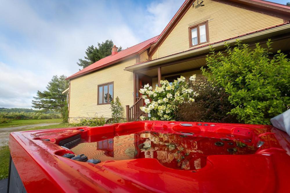 a back end of a red truck in front of a house at Camping de la Rivière Nicolet in Wotton