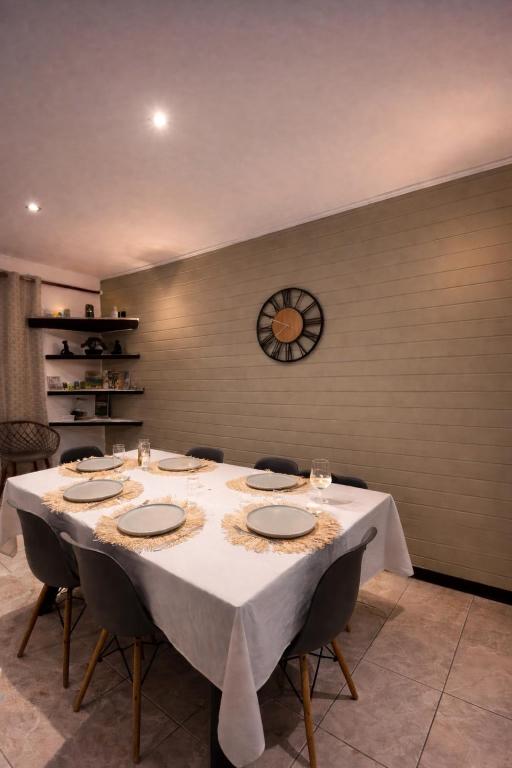 a long table with chairs and a clock on the wall at Là-Haut in Le Tampon