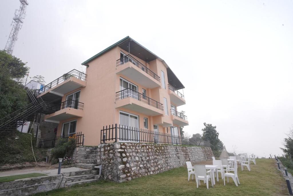 a building with tables and chairs in front of it at Corbett Valley View in Tota Ām