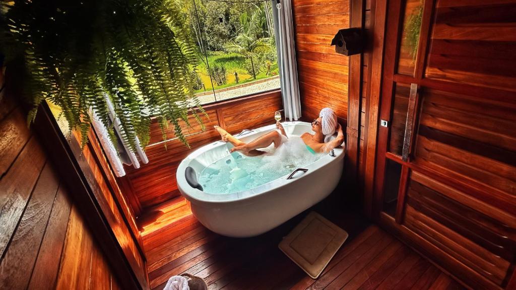 a woman sitting in a bath tub in a window at Chale Allegra - Hidro Aquecida - Vista para o Lago in Venda Nova do Imigrante