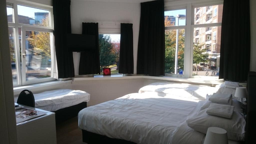 a bedroom with two beds and two windows at Hotel-Chao NL 24 hours open in Utrecht