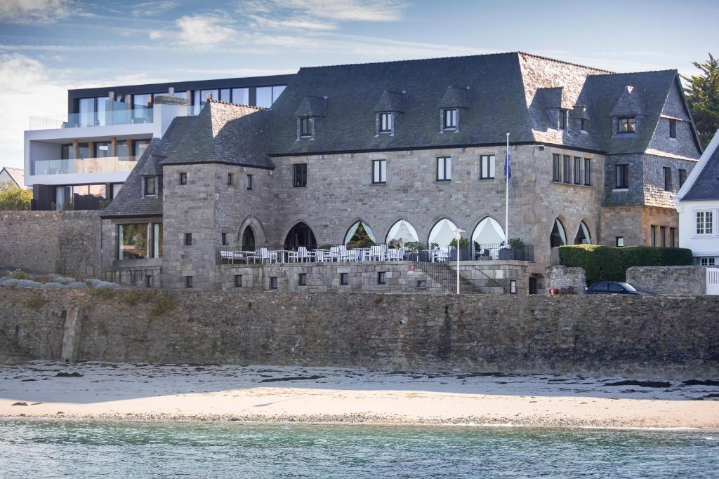 een groot stenen gebouw aan de oever van het water bij Relais & Châteaux Le Brittany & Spa in Roscoff