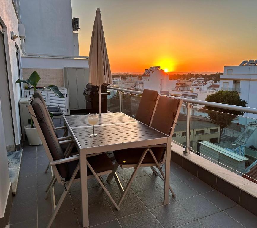 a table and chairs on a balcony with a sunset at Vela Terrace in Monte Gordo