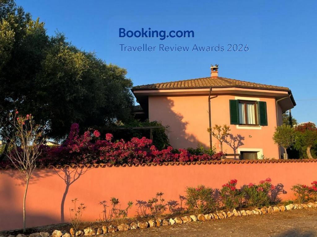 a house with a retaining wall and flowers at Domo Rosada in Ottava Sassari