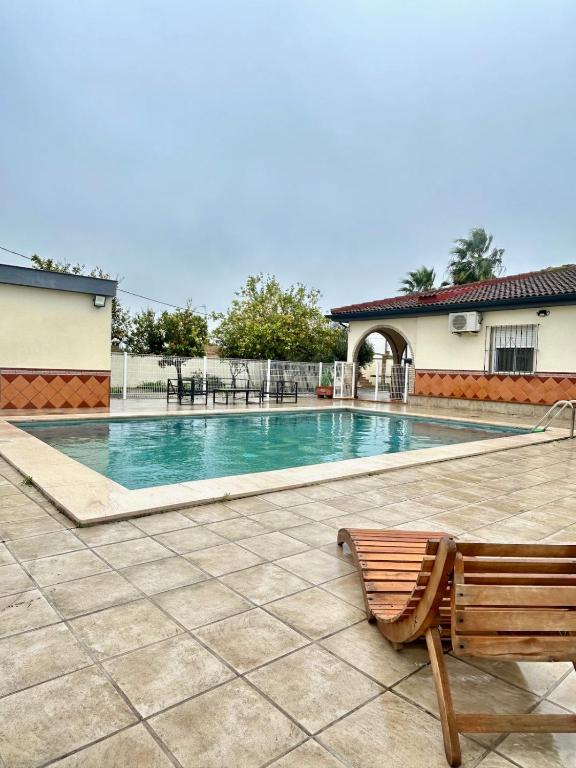 a swimming pool with a bench next to a building at Hispalis villa de Espartinas in Espartinas