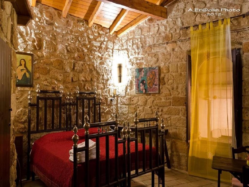 una camera con un letto rosso in una parete in pietra di B&B Pergulea a Sternatia