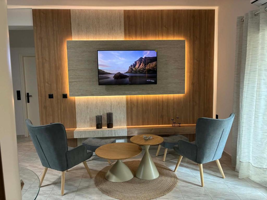 a living room with a table and a tv on a wall at Karadinos Apartment in Stílos