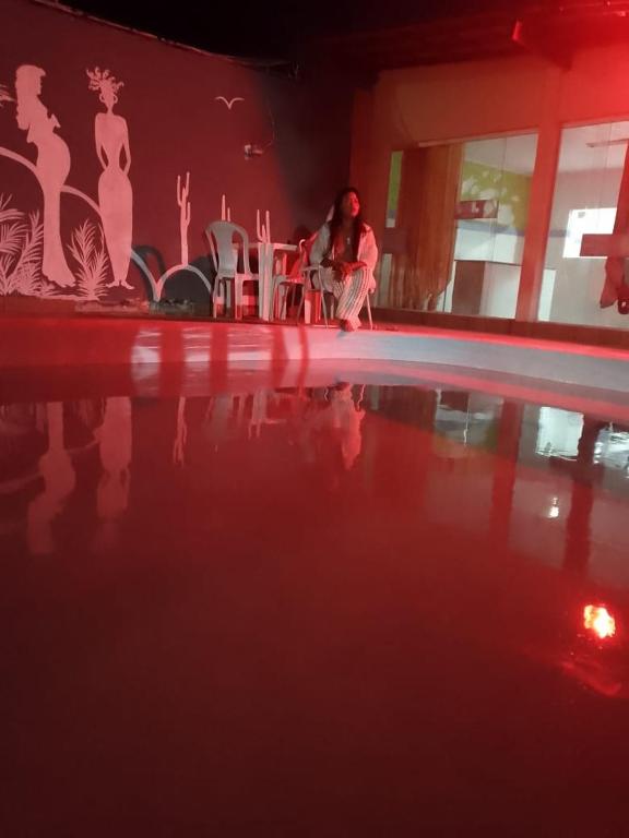 a person sitting at a table next to a swimming pool at Bio natura in Marechal Deodoro