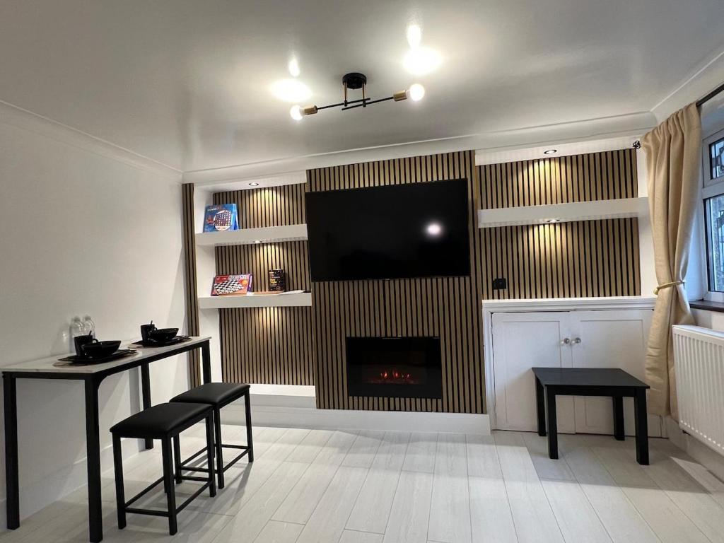 a living room with a fireplace and a flat screen tv at Intimate Hot Tub Pad in Swanscombe