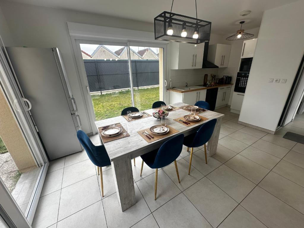 a dining room table with blue chairs in a kitchen at Maison individuelle parking privé et gratuit in Sainte-Savine